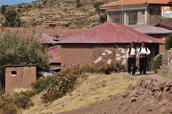 Com suas roupas típicas habitantes locais caminham pela Ilha de Taquile, no lago Titicaca, no Peru